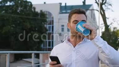 在<strong>办公大楼</strong>附近的停车场散步时，帅哥使用智能手机和喝美味的咖啡。 看上去